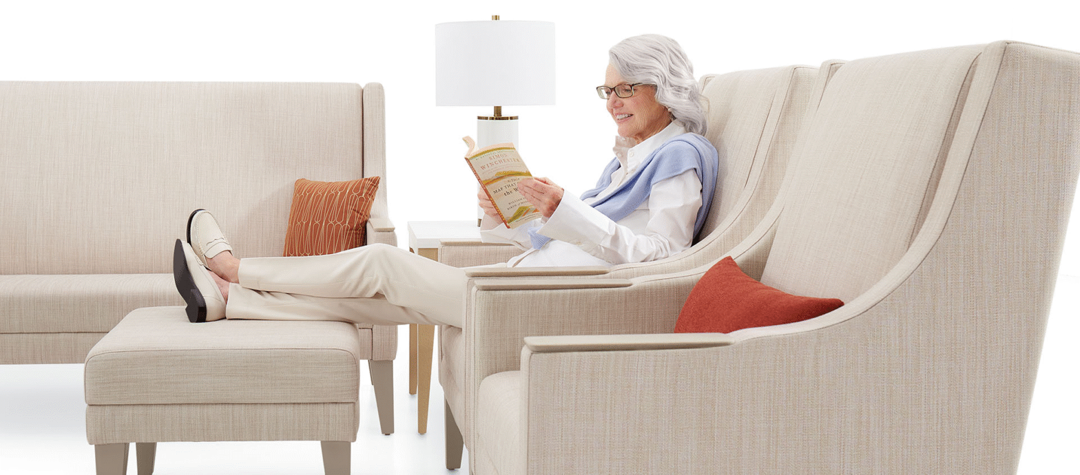 Senior woman relaxing on global furniture healthcare lounge seating in a bright, modern clinic, featuring comfortable global furniture and wellness-focused design.