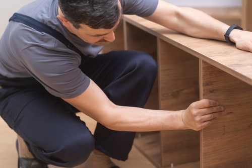 Technician assembling wooden office furniture Mississauga businesses use during a professional installation service.