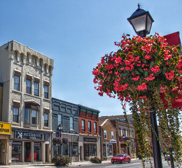 Historic Yonge Street storefronts in downtown Aurora Ontario with flower baskets, in the area served by The Office Shop for Aurora office furniture solutions