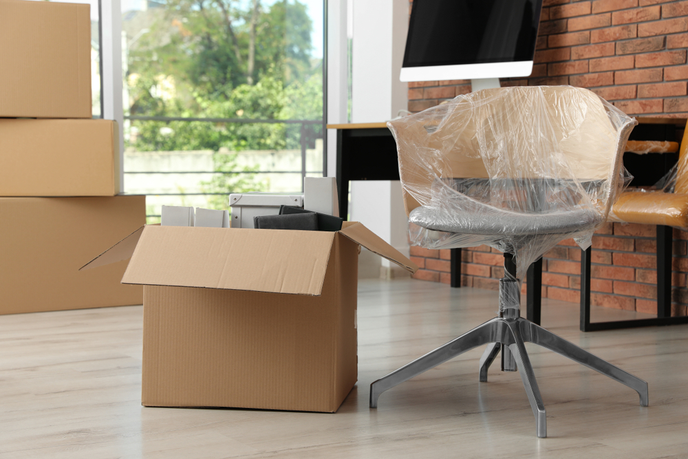 Packed office furniture and boxed equipment prepared for office furniture removal inside a commercial office space.