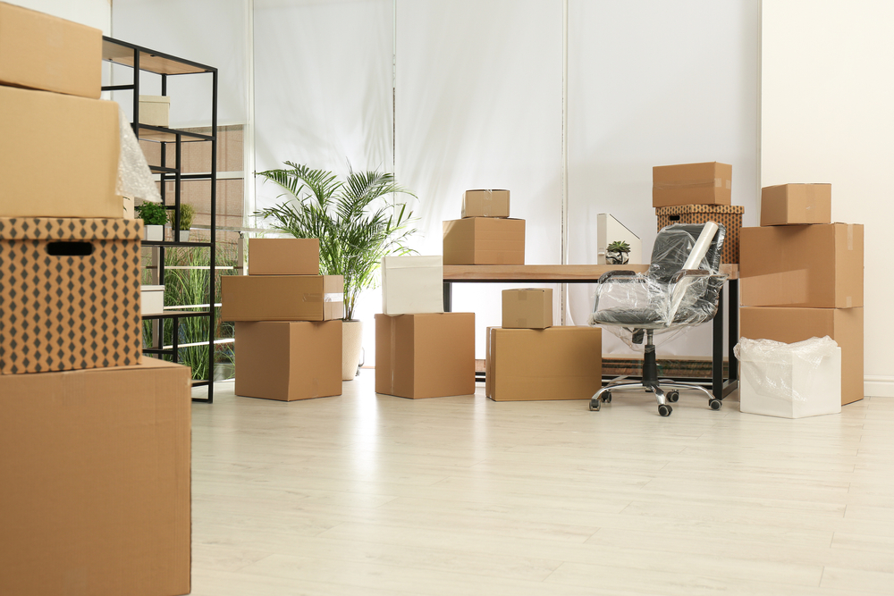 Packed office furniture and boxed equipment prepared for office furniture removal inside a commercial office space.