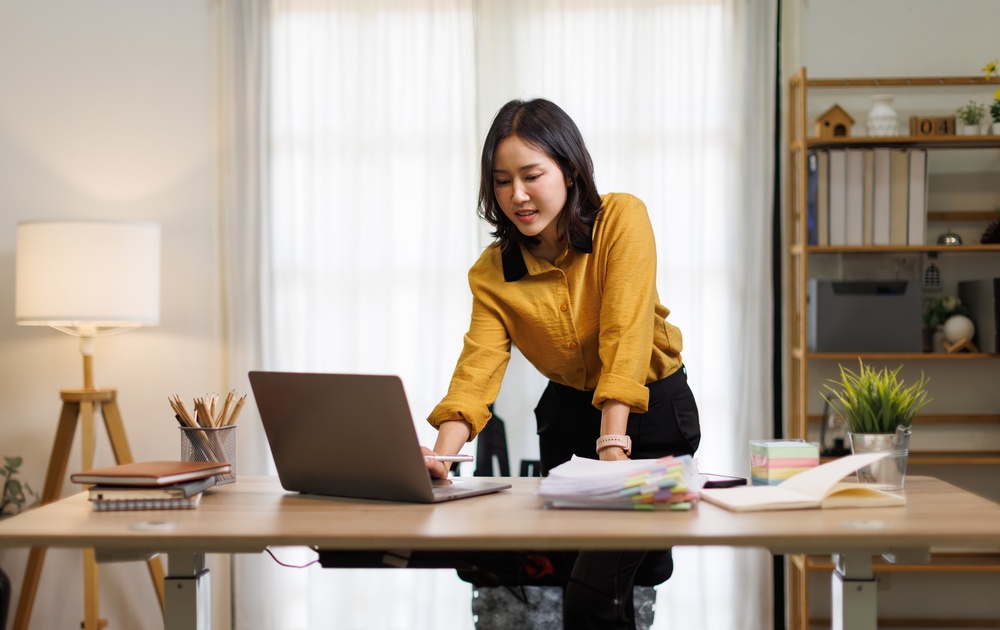 Employee raising a height adjustable desk to standing position in a Brampton workplace