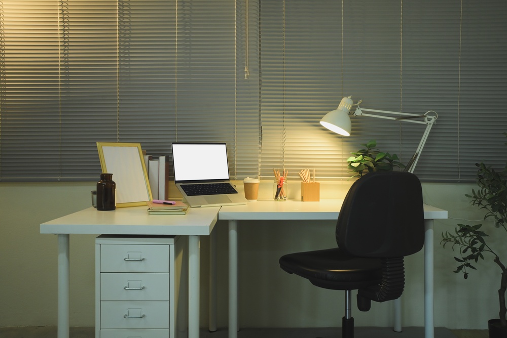 Height adjustable office desk with drawers beside an ergonomic chair